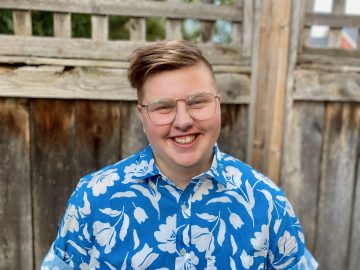 A smiling Kai Jacobsen wearing a blue shirt and glasses